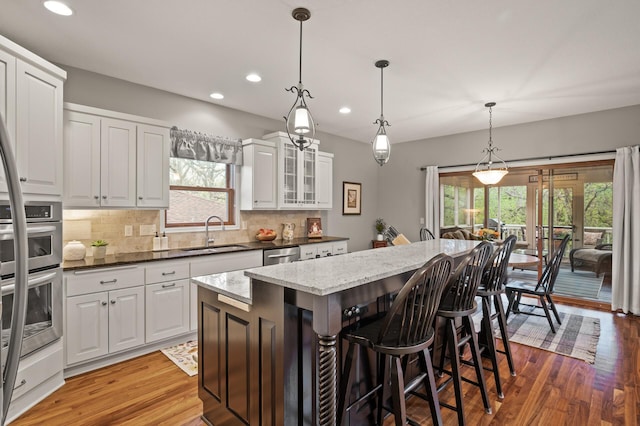 kitchen with tasteful backsplash, light wood-type flooring, a kitchen island, recessed lighting, and a sink