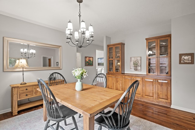 dining space with a notable chandelier, dark wood-style floors, and baseboards