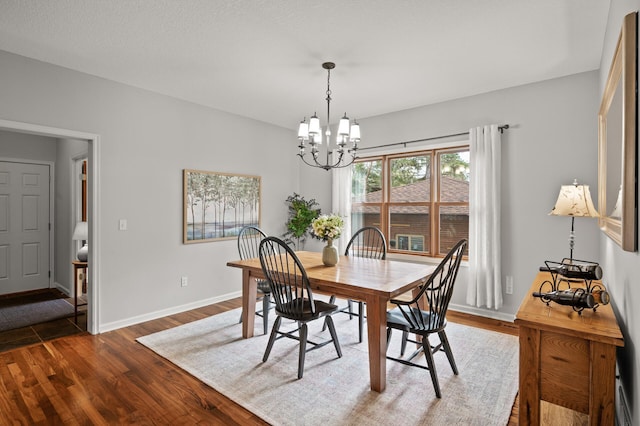 dining space featuring a chandelier, dark wood-type flooring, and baseboards