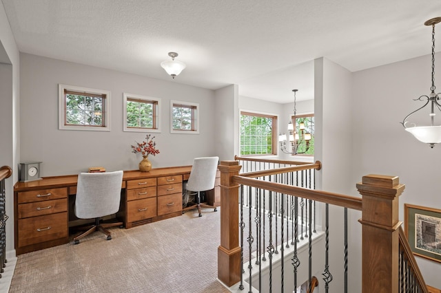 office featuring built in study area, a notable chandelier, and light carpet
