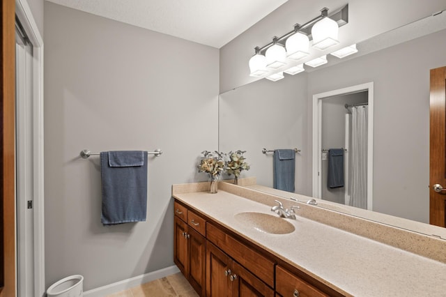 full bath featuring a shower with shower curtain, vanity, and baseboards