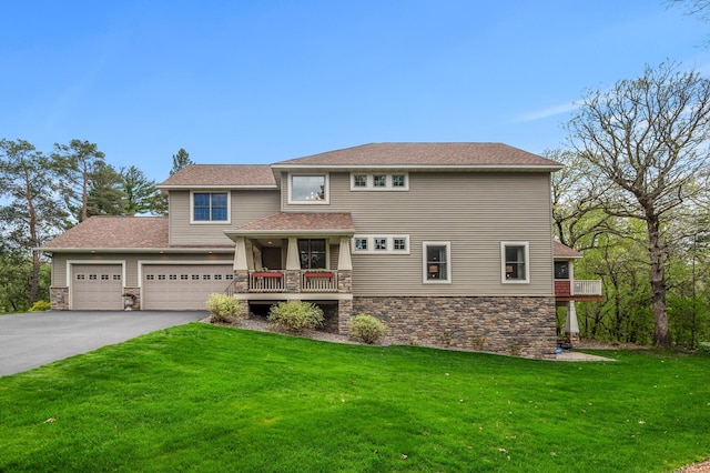 view of front of property with an attached garage, driveway, stone siding, and a front lawn