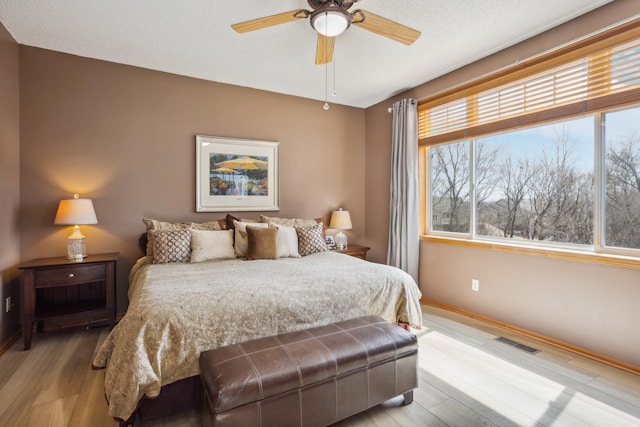 bedroom featuring light wood-style floors, baseboards, and ceiling fan