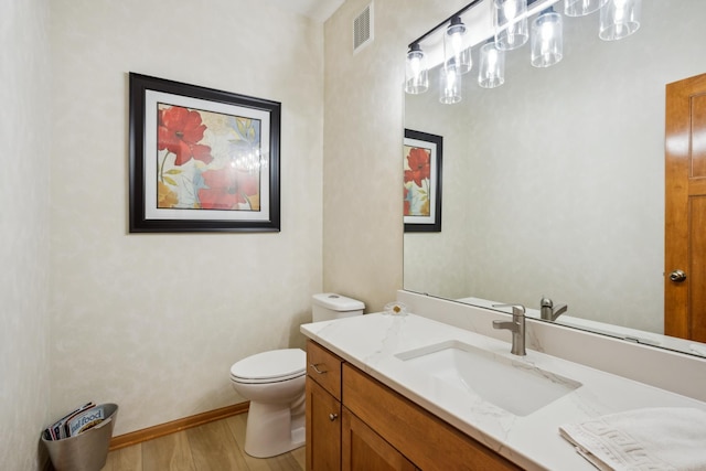 half bathroom featuring wood finished floors, toilet, vanity, and baseboards