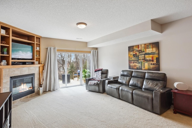 living area featuring carpet flooring, a tile fireplace, and a textured ceiling