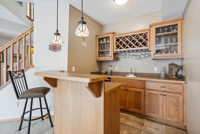 indoor wet bar with stairway, hanging light fixtures, and a textured ceiling