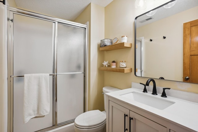 bathroom featuring a shower with shower door, toilet, vanity, and a textured ceiling