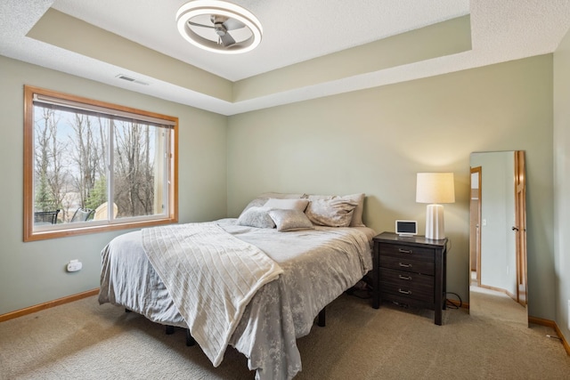 bedroom featuring baseboards, a tray ceiling, and carpet floors