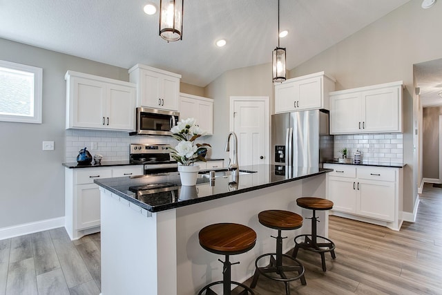 10017 177th Ave NW, Elk River, MN 55330 - kitchen with stainless steel appliances, light wood-style flooring, vaulted ceiling, and dark countertops