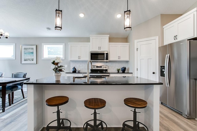 10017 177th Ave NW, Elk River, MN 55330 - kitchen with a kitchen breakfast bar, light wood-style flooring, a sink, stainless steel appliances, and decorative backsplash