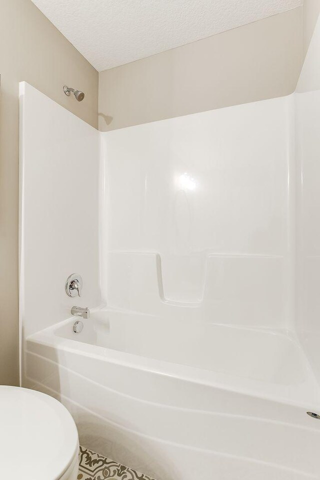 10017 177th Ave NW, Elk River, MN 55330 - full bathroom featuring shower / bathtub combination, a textured ceiling, and toilet