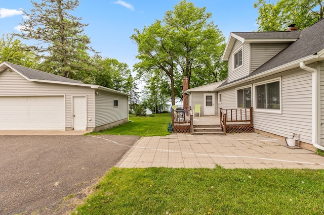 42271 Vista Road, East Side Twp, MN 56342 - view of grassy yard featuring a deck, an outbuilding, a garage, and a patio area