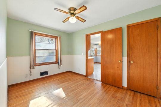 7335 Penn Ave S, Richfield, MN 55423 - unfurnished bedroom featuring wood finished floors, a ceiling fan, visible vents, and a wainscoted wall