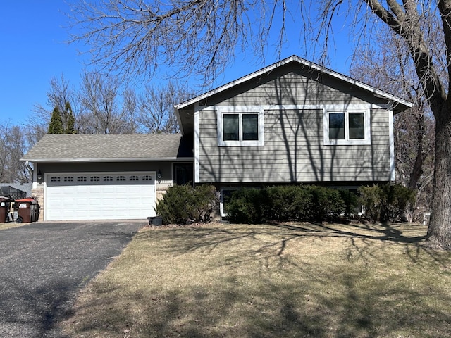 split level home featuring driveway, an attached garage, and a front lawn