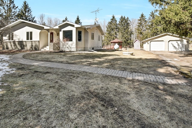 view of front of house featuring a garage, stucco siding, and an outdoor structure