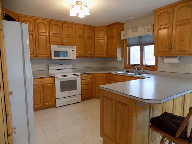 kitchen with a sink, a kitchen breakfast bar, white appliances, a peninsula, and light floors