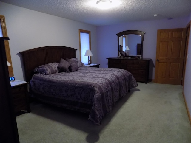 bedroom with a textured ceiling and light colored carpet