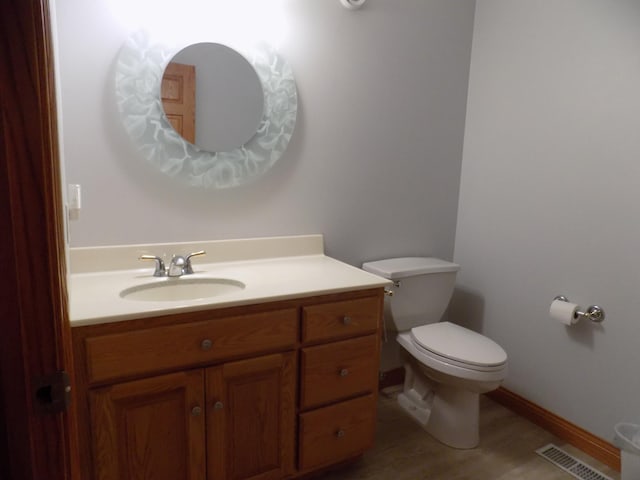bathroom featuring visible vents, toilet, vanity, and wood finished floors