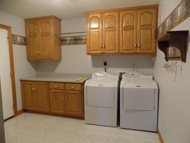 laundry area with light floors, a textured ceiling, washing machine and clothes dryer, baseboards, and cabinet space