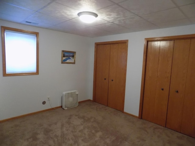 unfurnished bedroom featuring two closets, baseboards, visible vents, and carpet floors