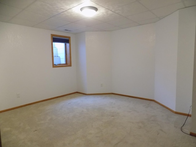 carpeted empty room with baseboards and a drop ceiling