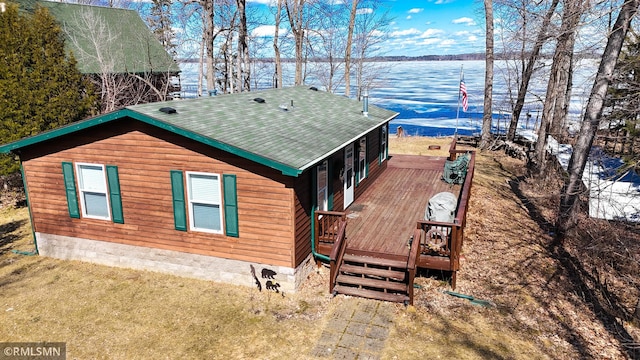 rear view of house featuring a shingled roof and a water view