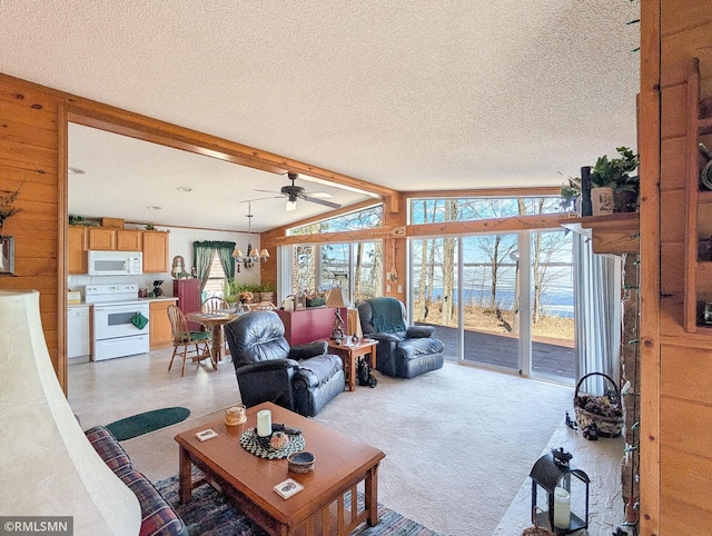 living room featuring ceiling fan with notable chandelier, vaulted ceiling with beams, light colored carpet, and a textured ceiling