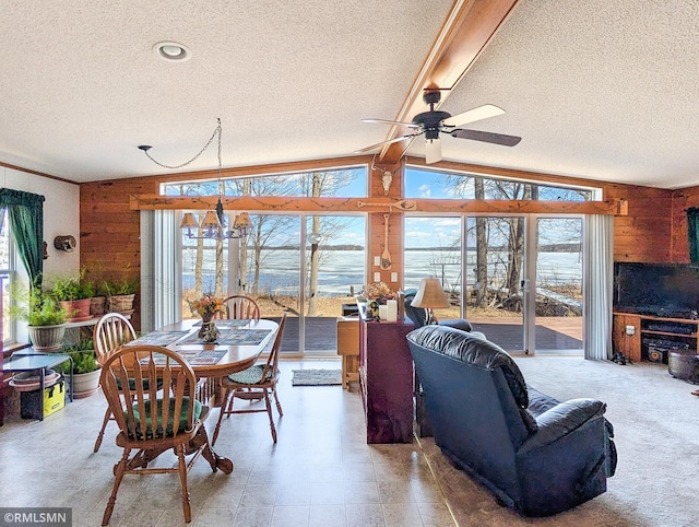 interior space with wood walls, ceiling fan, vaulted ceiling with beams, and a wealth of natural light