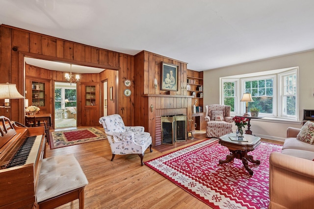 19135 Highland Ave, Deephaven, MN 55391 - living room featuring wooden walls, a fireplace, a chandelier, and light wood-style floors