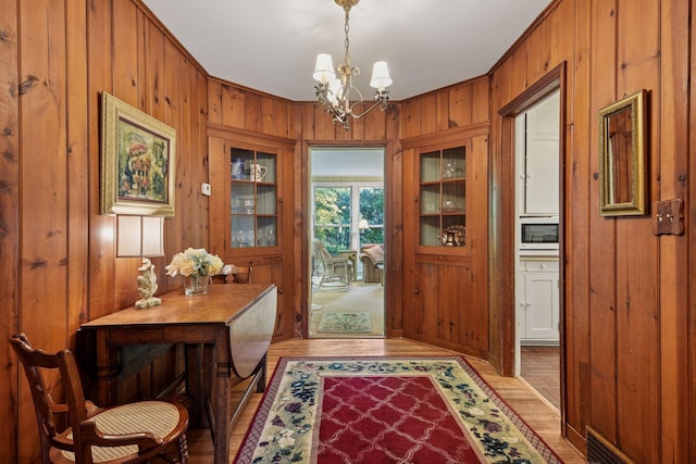 19135 Highland Ave, Deephaven, MN 55391 - entrance foyer with wooden walls, a chandelier, and light wood-style flooring