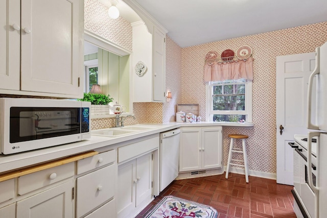 19135 Highland Ave, Deephaven, MN 55391 - kitchen featuring white appliances, wallpapered walls, white cabinetry, light countertops, and brick patterned floors