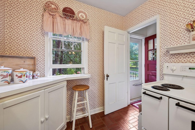 19135 Highland Ave, Deephaven, MN 55391 - kitchen featuring wallpapered walls, electric range, light countertops, brick patterned flooring, and plenty of natural light