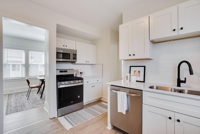 kitchen featuring a sink, white cabinets, tasteful backsplash, and stainless steel appliances