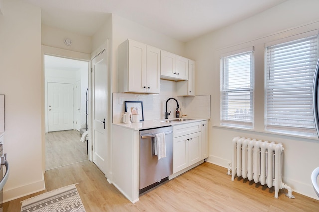 kitchen with stainless steel dishwasher, a sink, light countertops, light wood-style floors, and radiator