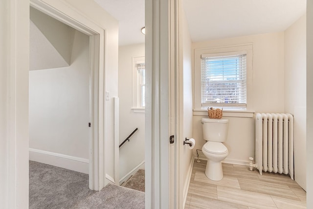 bathroom featuring radiator, baseboards, and toilet