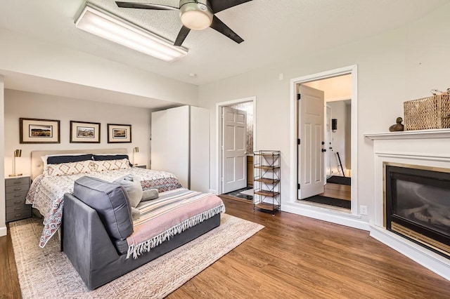 7488 Hydram Ave S, Cottage Grove, MN 55016 - bedroom featuring wood finished floors, a glass covered fireplace, ceiling fan, and baseboards