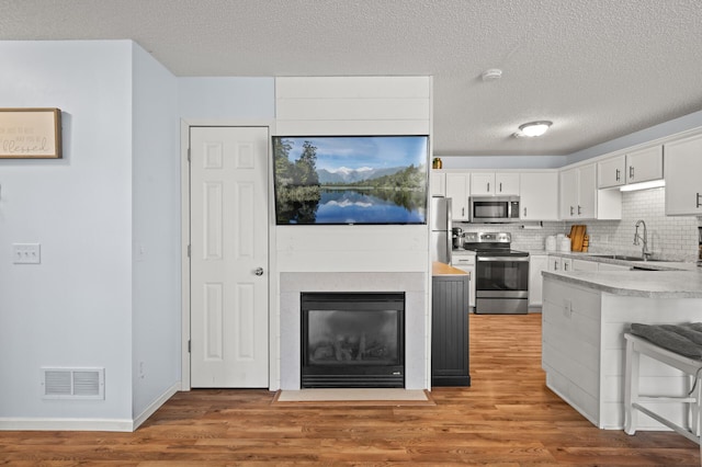 1324 Pembrooke Ln, Waconia, MN 55387 - kitchen featuring appliances with stainless steel finishes, light wood-style floors, light countertops, a textured ceiling, and white cabinets