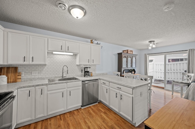 1324 Pembrooke Ln, Waconia, MN 55387 - kitchen with stainless steel dishwasher, light countertops, a peninsula, white cabinets, and decorative backsplash
