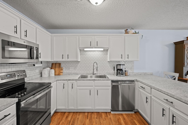 1324 Pembrooke Ln, Waconia, MN 55387 - kitchen featuring appliances with stainless steel finishes, white cabinetry, light wood finished floors, and a textured ceiling