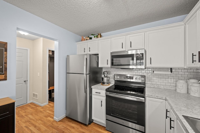 1324 Pembrooke Ln, Waconia, MN 55387 - kitchen with stainless steel appliances, light countertops, light wood-style floors, white cabinetry, and tasteful backsplash