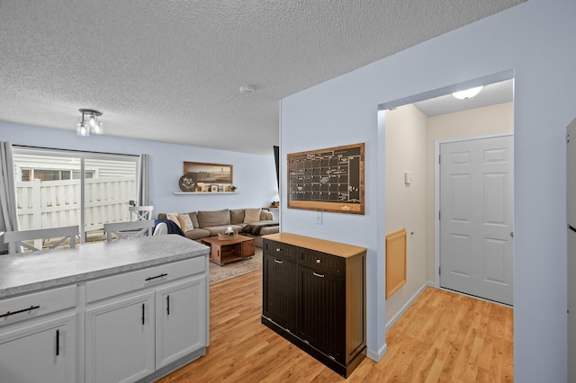 1324 Pembrooke Ln, Waconia, MN 55387 - kitchen with light wood finished floors, a textured ceiling, light countertops, and white cabinetry