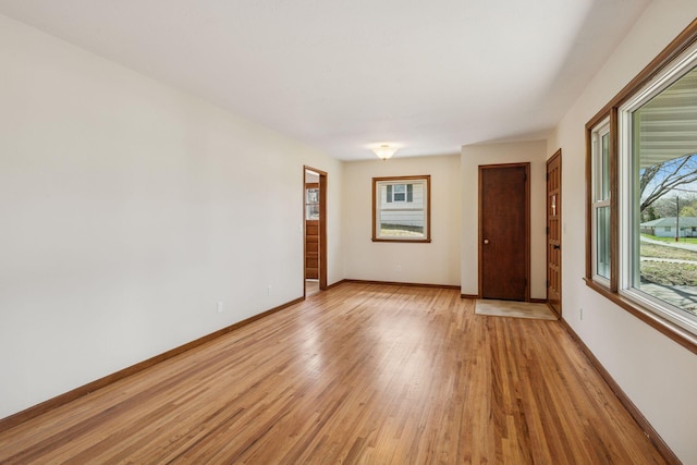 spare room featuring baseboards and light wood-style floors