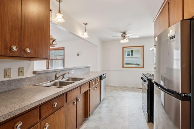 kitchen with a sink, light floors, appliances with stainless steel finishes, and a healthy amount of sunlight