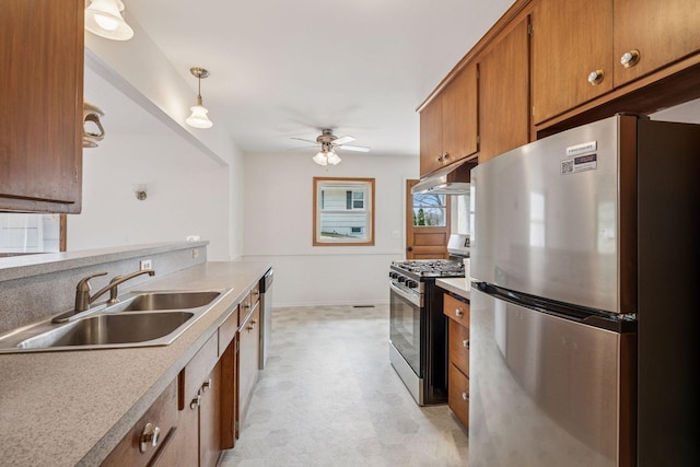 kitchen with brown cabinetry, light floors, ceiling fan, a sink, and stainless steel appliances