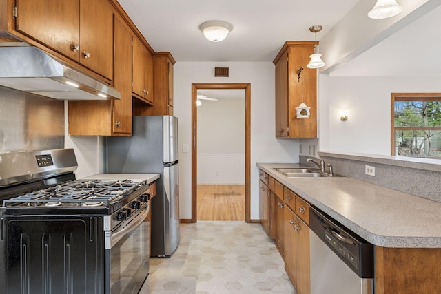 kitchen featuring under cabinet range hood, appliances with stainless steel finishes, brown cabinetry, and a sink
