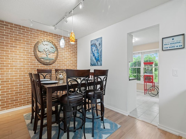 11004 Oregon Curv, Bloomington, MN 55438 - dining area with brick wall, wood finished floors, rail lighting, and a textured ceiling
