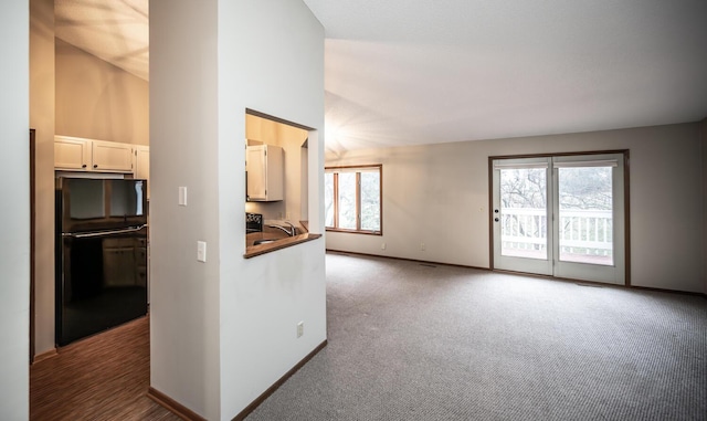 kitchen with carpet flooring, dark countertops, freestanding refrigerator, baseboards, and open floor plan