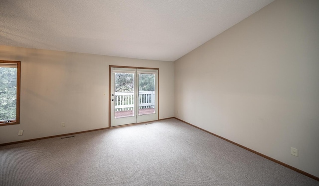 empty room featuring a wealth of natural light, light colored carpet, and baseboards