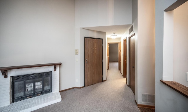 hallway with carpet, visible vents, baseboards, and a high ceiling