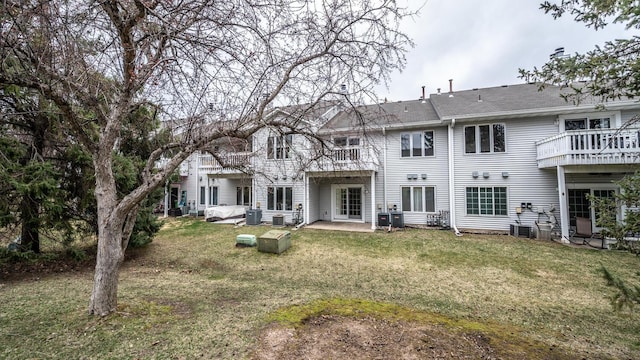 rear view of property featuring central AC, a balcony, and a lawn